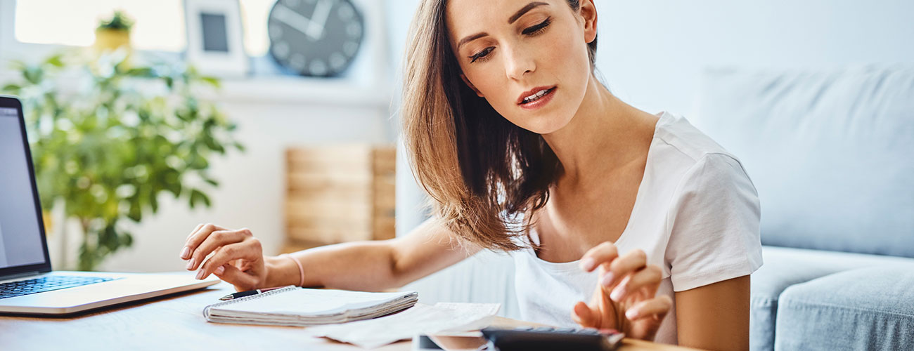 Young woman using a calculator to calculate her finances.